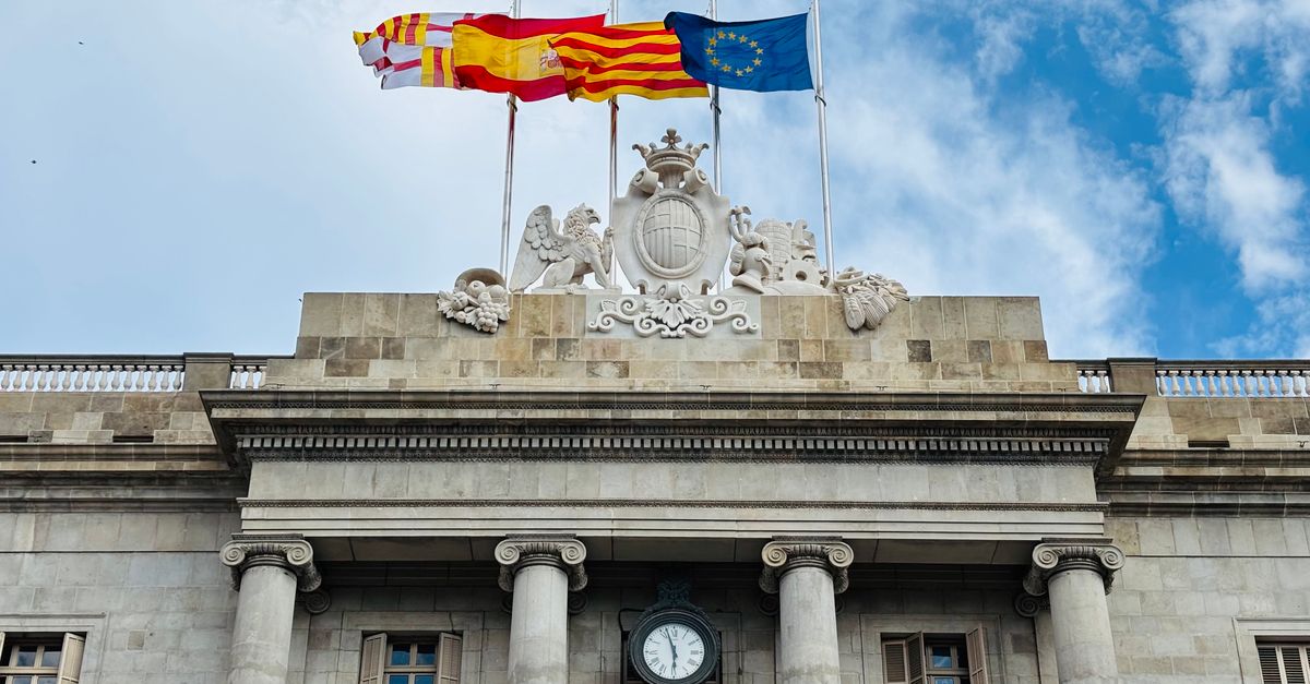 Fachada de un edificio institucional con las banderas de Europa y de España, símbolo de la autoridad española que supervisa la IA